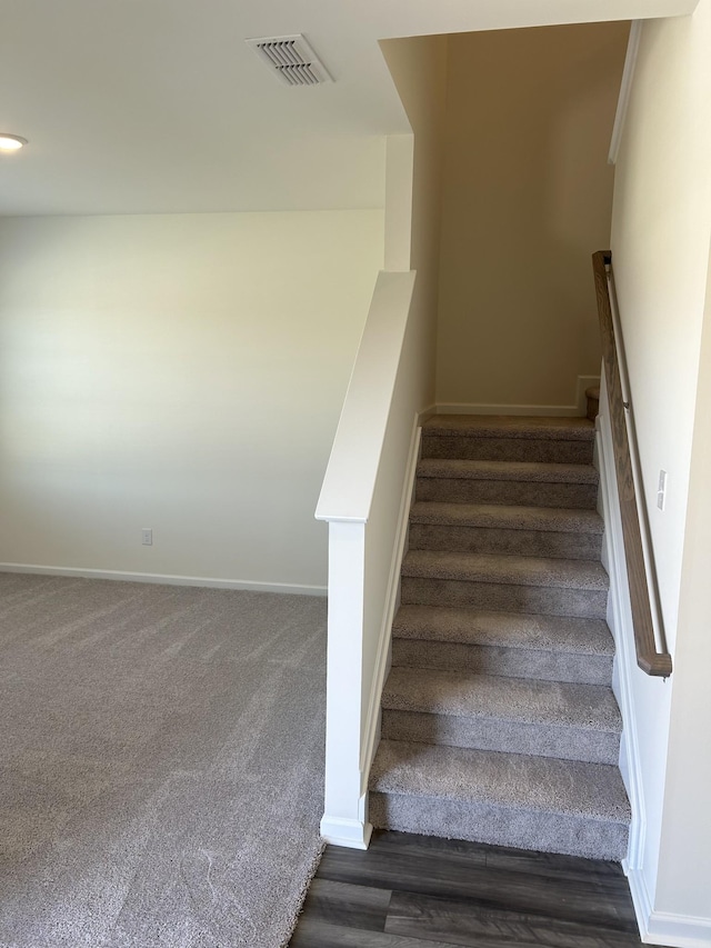 staircase with baseboards, visible vents, and carpet floors