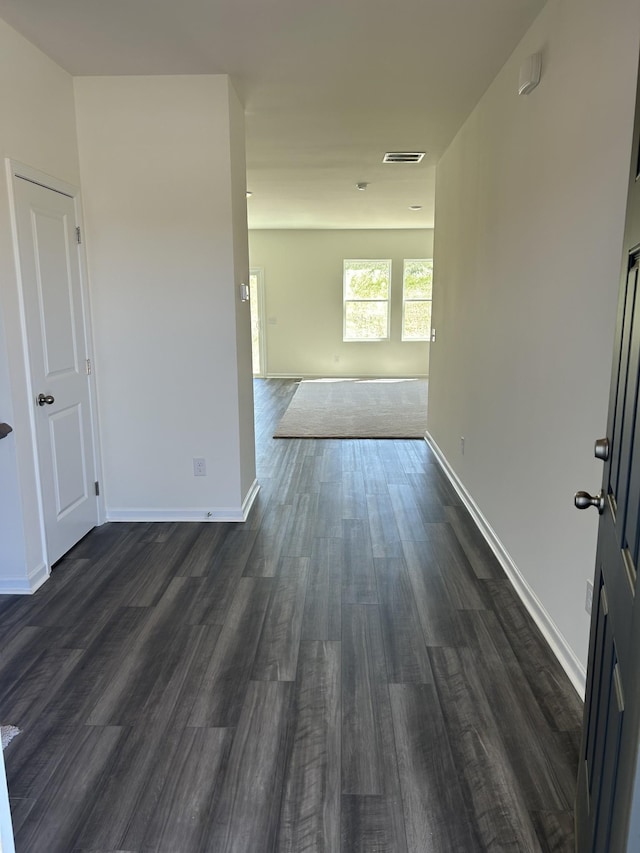 empty room featuring dark wood-type flooring and baseboards