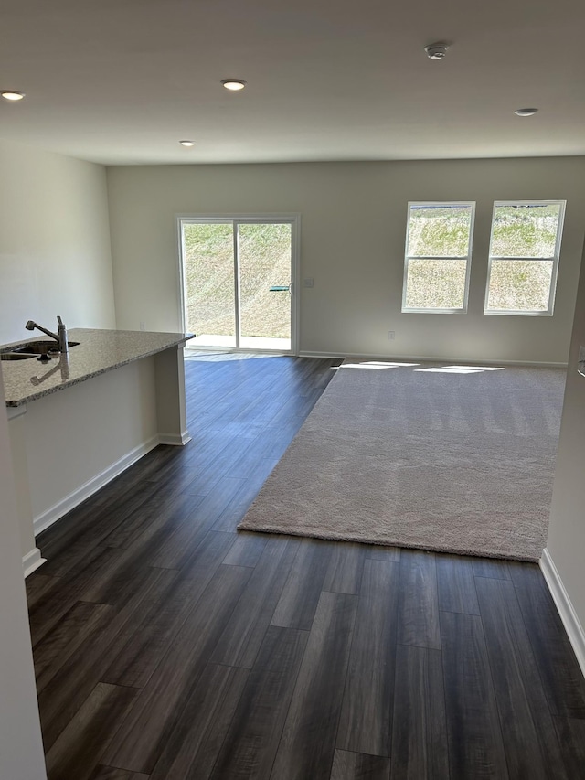 empty room featuring dark wood-style floors, recessed lighting, and a sink