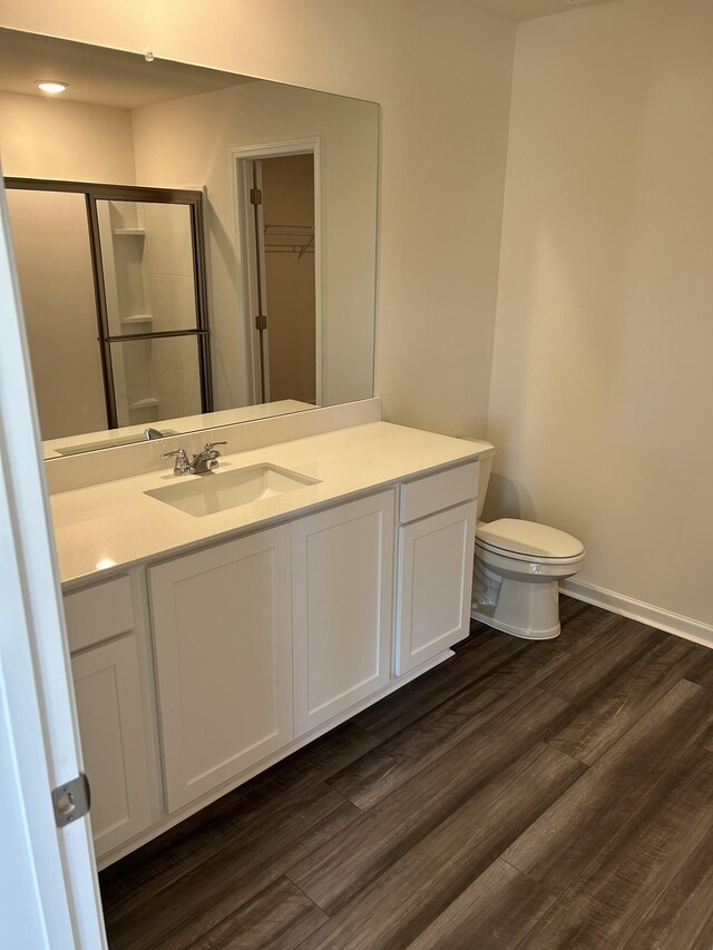 full bath with a shower stall, baseboards, wood finished floors, toilet, and vanity