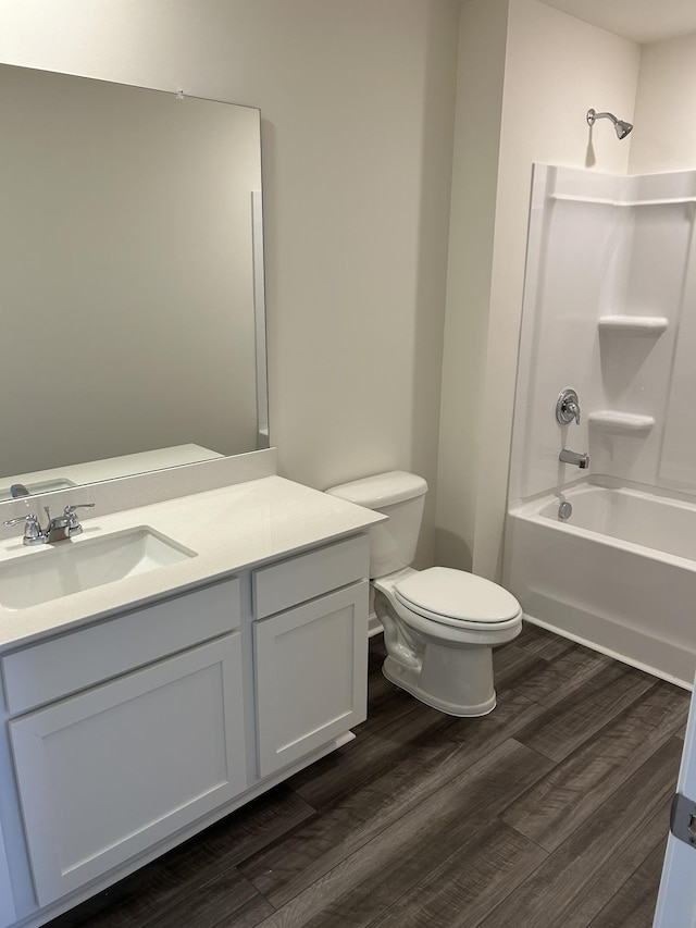 bathroom featuring wood finished floors, toilet, vanity, and shower / washtub combination