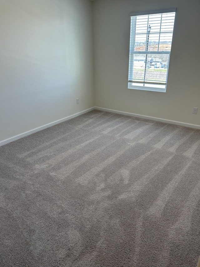 empty room featuring baseboards and carpet