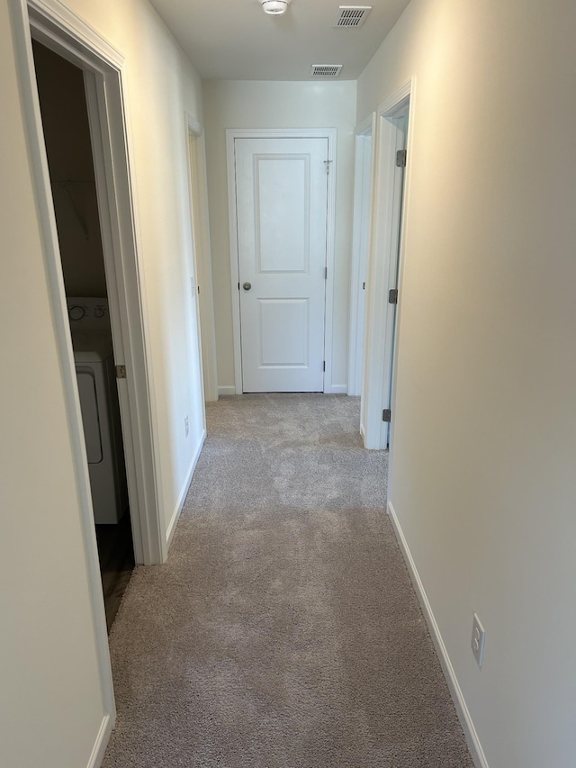 hallway featuring baseboards, carpet, visible vents, and washer / dryer