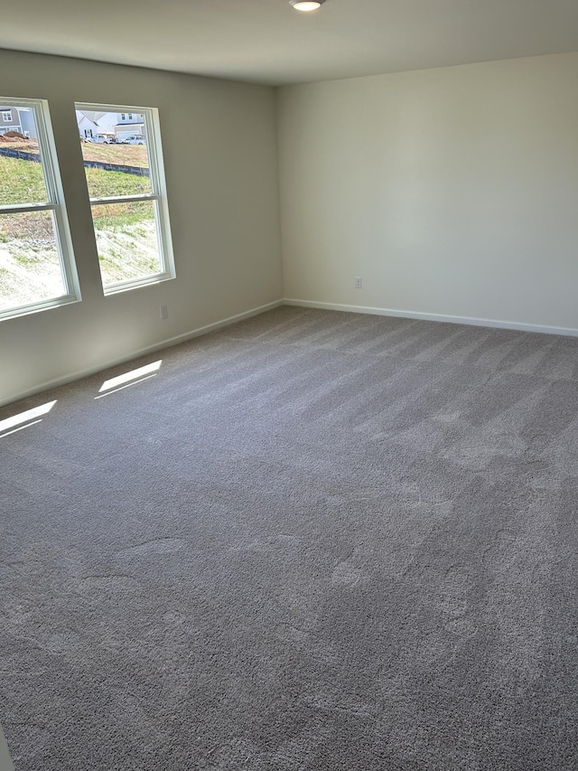 empty room featuring carpet and baseboards