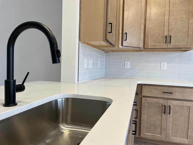 interior details with light stone countertops, sink, and decorative backsplash