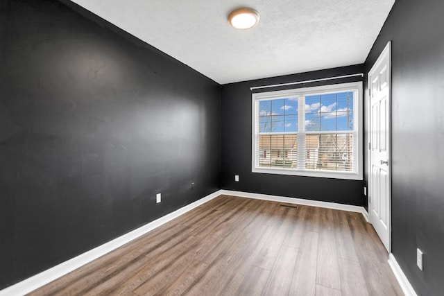 spare room with hardwood / wood-style floors and a textured ceiling