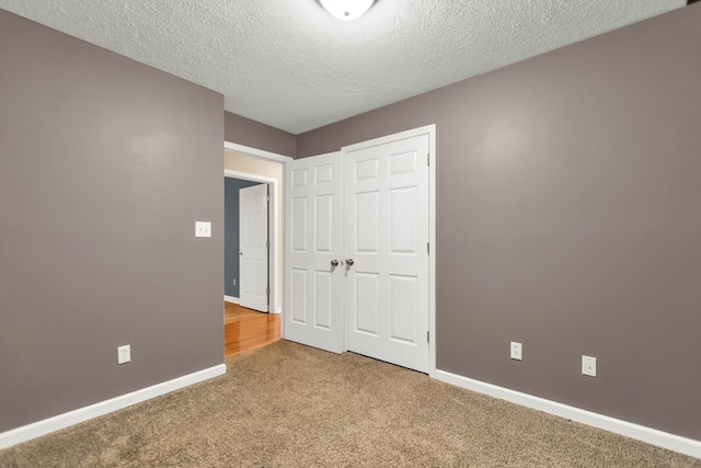 unfurnished bedroom featuring a closet, carpet, and a textured ceiling