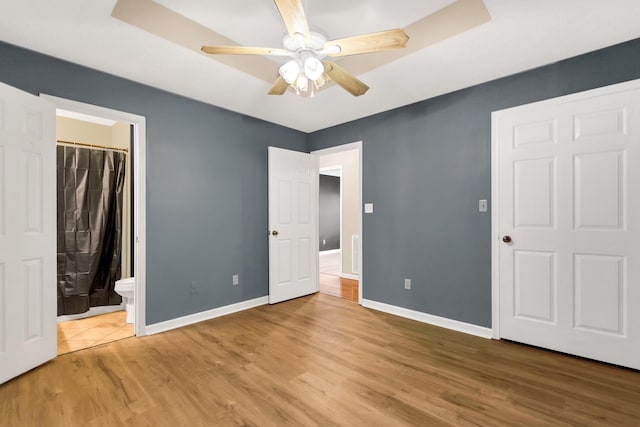 unfurnished bedroom with light hardwood / wood-style floors, ceiling fan, and ensuite bathroom