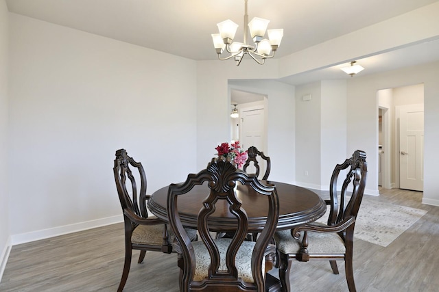 dining room featuring a notable chandelier, baseboards, and wood finished floors