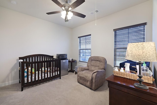 bedroom with baseboards, visible vents, a ceiling fan, light colored carpet, and a nursery area