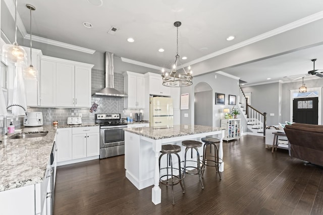 kitchen with stainless steel electric stove, a kitchen island, sink, white refrigerator, and wall chimney exhaust hood