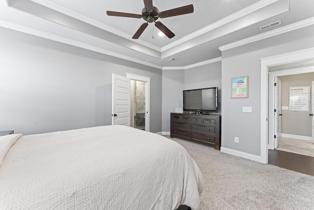 bedroom with ensuite bath, ceiling fan, carpet flooring, a tray ceiling, and ornamental molding