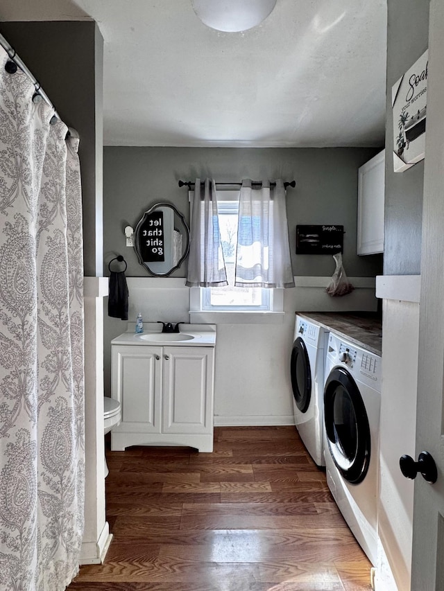 clothes washing area with dark hardwood / wood-style floors, cabinets, sink, and washing machine and dryer