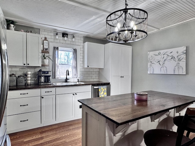 kitchen with sink, stainless steel dishwasher, hanging light fixtures, and white cabinets