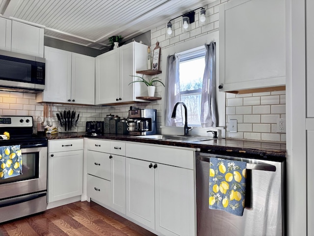 kitchen with dark wood-type flooring, sink, white cabinetry, stainless steel appliances, and decorative backsplash