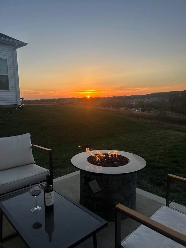 patio terrace at dusk with a lawn and an outdoor fire pit