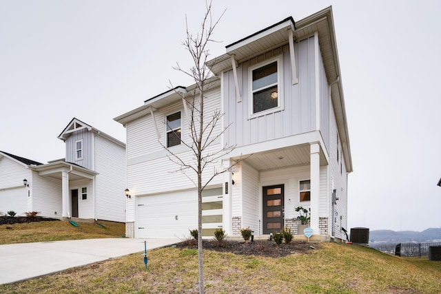 view of front of property with a garage, a porch, cooling unit, and a front yard