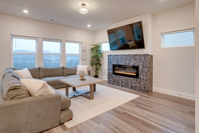 living room with light hardwood / wood-style flooring and a premium fireplace