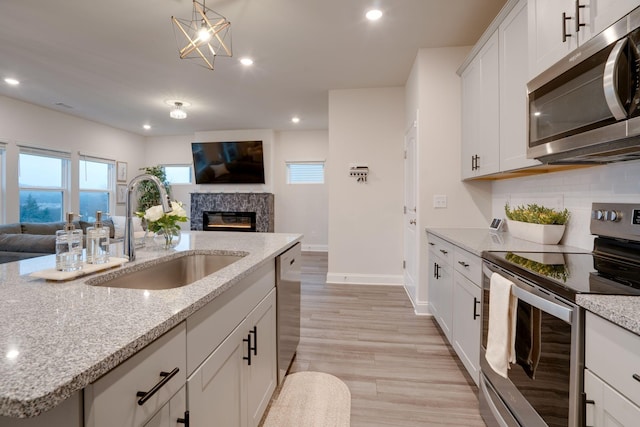 kitchen featuring white cabinetry, an island with sink, sink, decorative backsplash, and stainless steel appliances