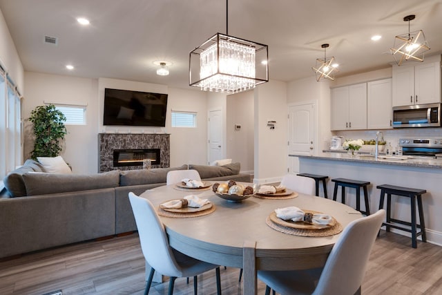 dining space featuring light hardwood / wood-style flooring, sink, and a fireplace