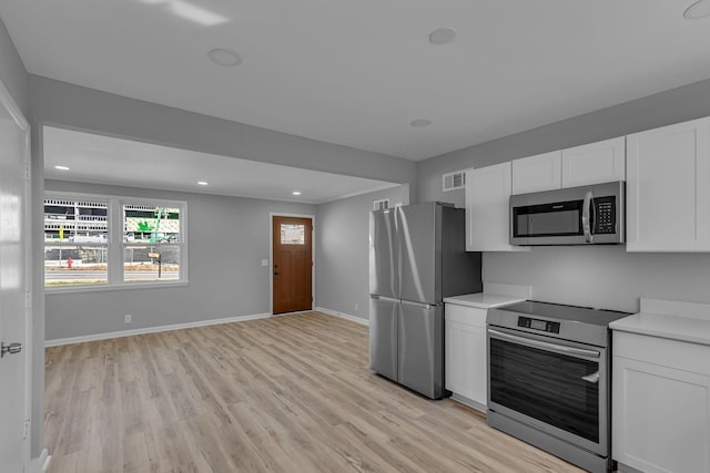 kitchen with stainless steel appliances, light hardwood / wood-style floors, and white cabinets