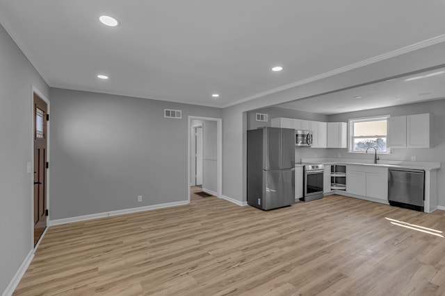 kitchen featuring sink, light hardwood / wood-style flooring, ornamental molding, stainless steel appliances, and white cabinets