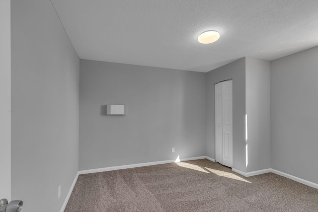 carpeted empty room with a textured ceiling