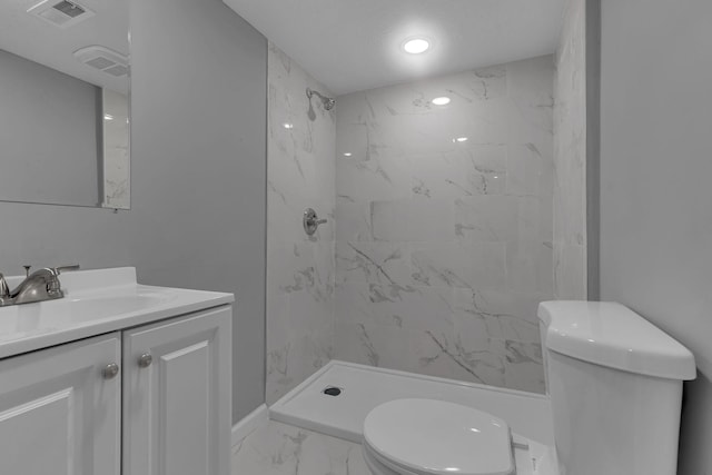 bathroom with vanity, tiled shower, and toilet