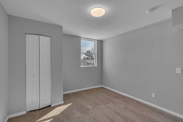 unfurnished bedroom with carpet flooring, a textured ceiling, and a closet