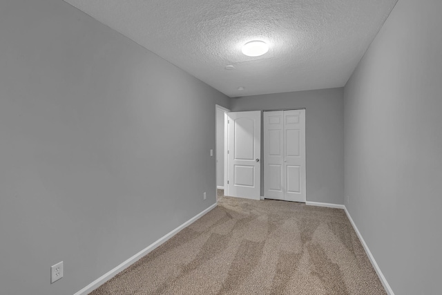 unfurnished bedroom featuring light carpet, a textured ceiling, and a closet