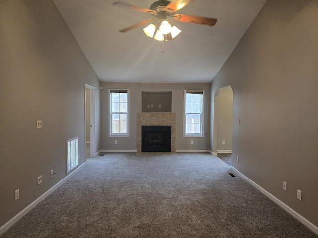 unfurnished living room featuring a tile fireplace, light carpet, ceiling fan, and high vaulted ceiling