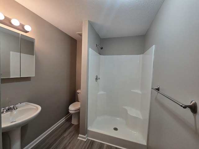 bathroom with sink, wood-type flooring, a textured ceiling, a shower, and toilet