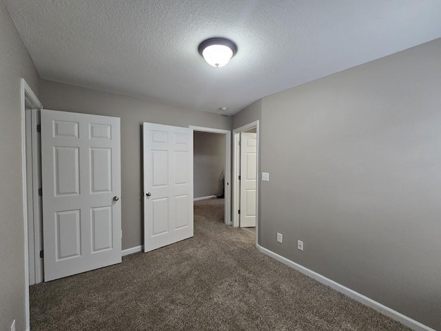 unfurnished bedroom featuring dark colored carpet and a textured ceiling