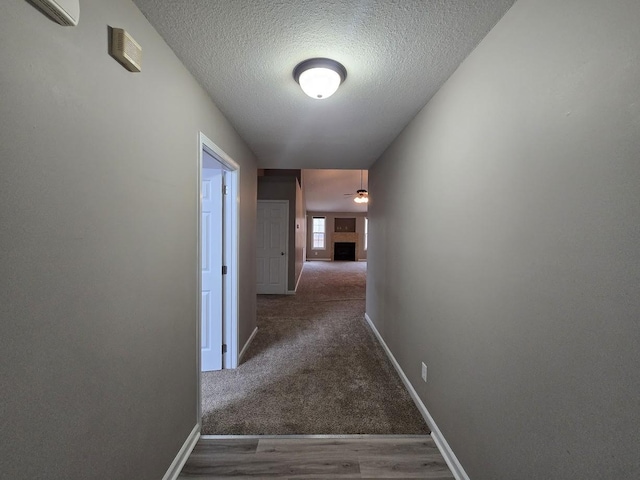 hallway featuring dark hardwood / wood-style floors, a wall mounted AC, and a textured ceiling