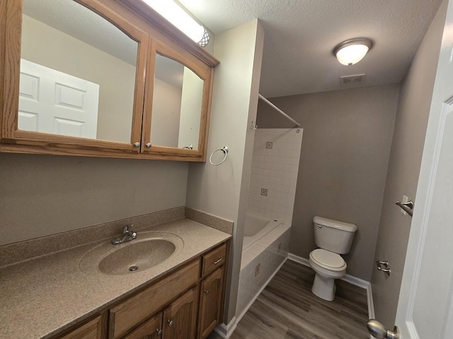 full bathroom featuring hardwood / wood-style flooring, vanity, a textured ceiling, shower / bathtub combination, and toilet