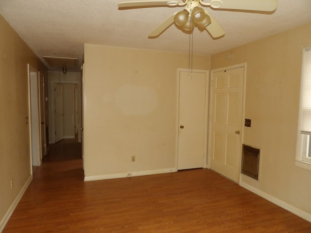 empty room with hardwood / wood-style flooring, heating unit, a textured ceiling, and ceiling fan