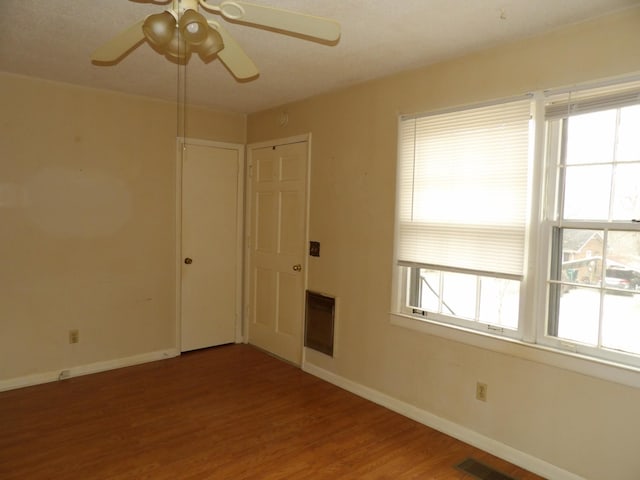 spare room with hardwood / wood-style flooring, plenty of natural light, heating unit, and ceiling fan