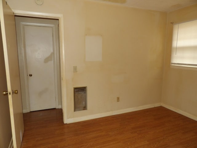 spare room with heating unit and dark hardwood / wood-style flooring