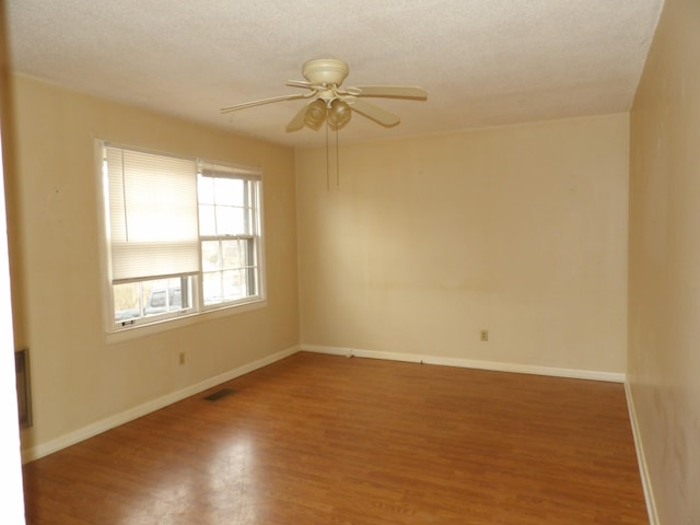 spare room with ceiling fan, wood-type flooring, and a textured ceiling