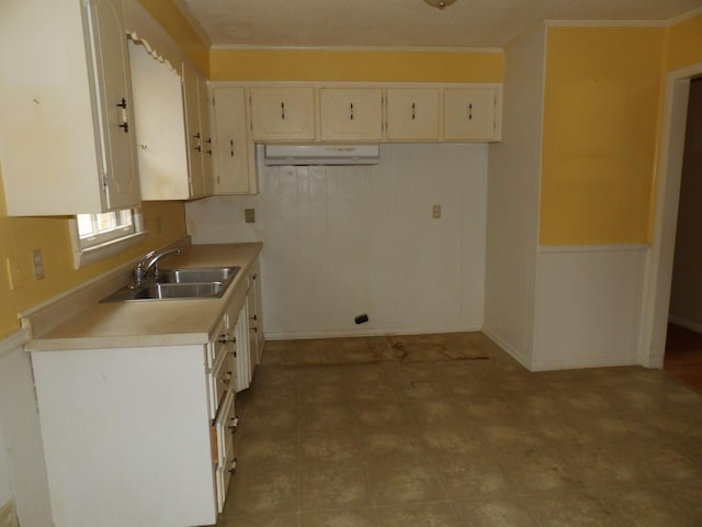 kitchen with crown molding, sink, and white cabinets