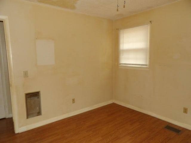 spare room featuring heating unit and wood-type flooring