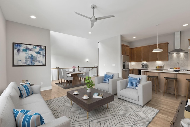 living room featuring sink, light hardwood / wood-style flooring, and ceiling fan