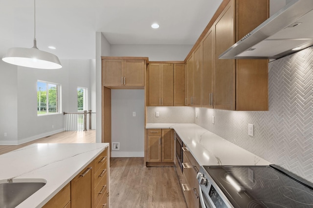 kitchen with electric stove, pendant lighting, backsplash, light stone counters, and wall chimney exhaust hood