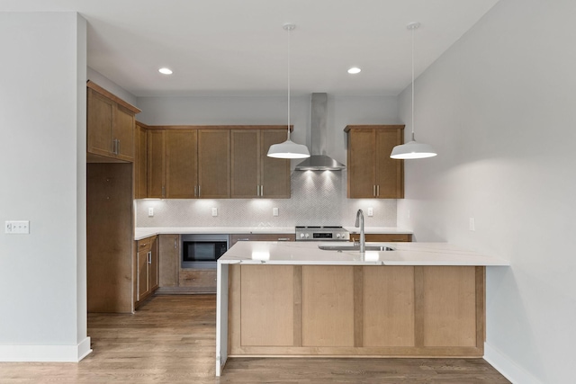 kitchen with decorative light fixtures, built in microwave, sink, decorative backsplash, and wall chimney exhaust hood