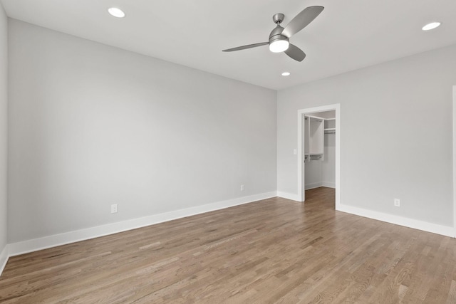 unfurnished bedroom with a walk in closet, light hardwood / wood-style floors, a closet, and ceiling fan