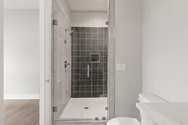 bathroom with toilet, an enclosed shower, and hardwood / wood-style floors