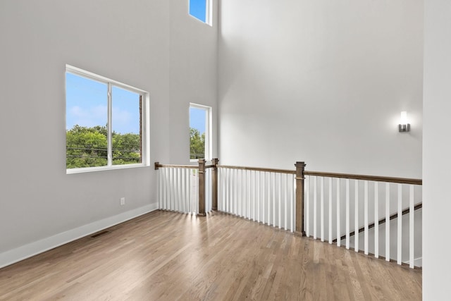 unfurnished room with a towering ceiling and light wood-type flooring