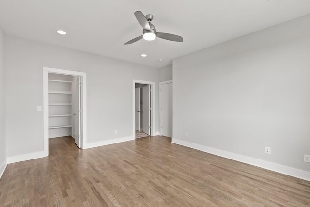 unfurnished bedroom featuring a spacious closet, light hardwood / wood-style flooring, and ceiling fan