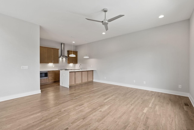 unfurnished living room with ceiling fan, sink, and light wood-type flooring