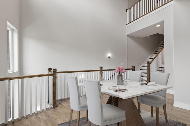 dining space with a high ceiling and light hardwood / wood-style floors